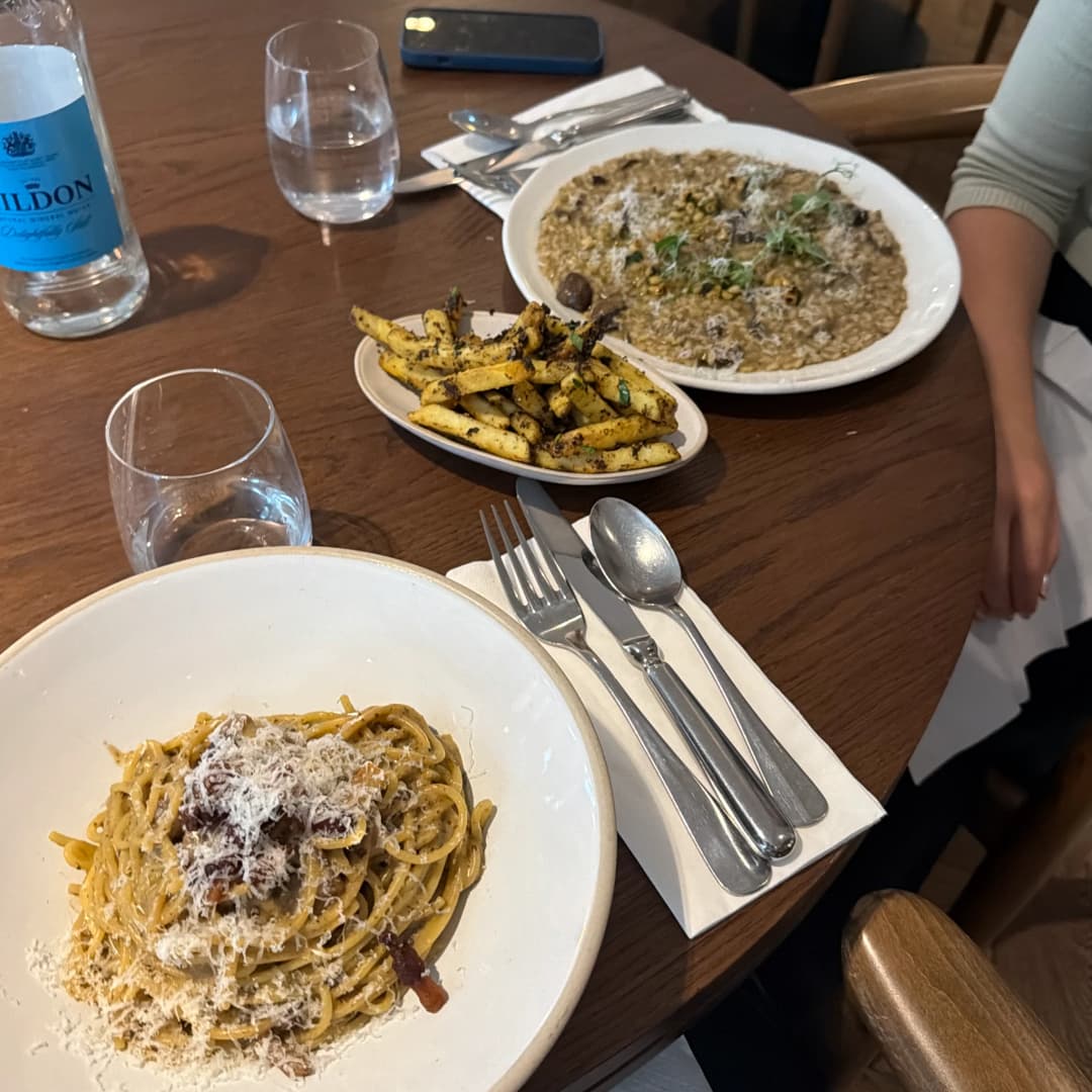 Carbonara, mushroom risotto and truffle fries on a wooden table at Kendal Street Kitchen