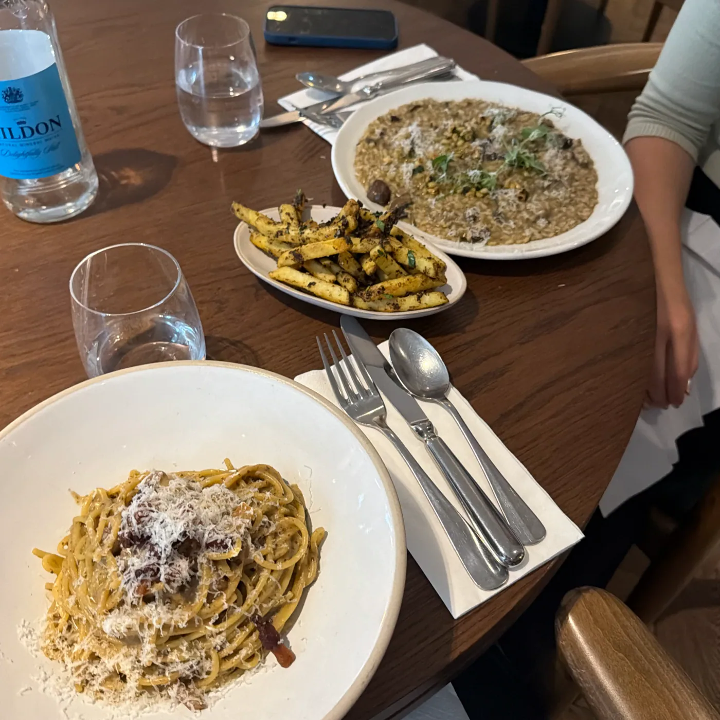 Carbonara, mushroom risotto and truffle fries on a wooden table at Kendal Street Kitchen