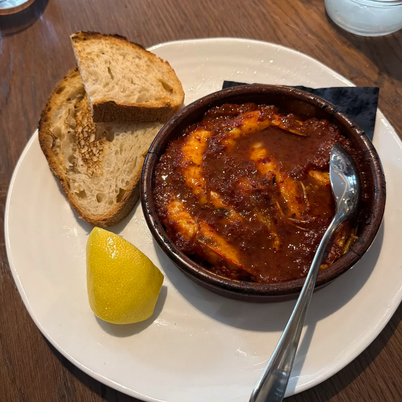 Harissa prawns in a terracotta dish with grilled sourdough and lemon at Kendal Street Kitchen